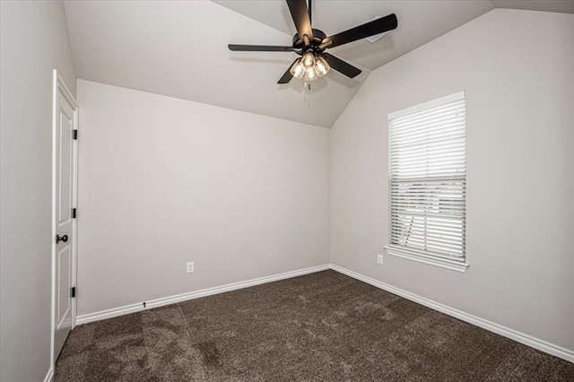 empty room featuring vaulted ceiling, ceiling fan, dark colored carpet, healthy amount of natural light, and baseboards