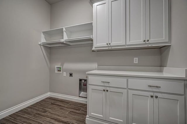 clothes washing area with electric dryer hookup, cabinet space, washer hookup, baseboards, and dark wood-type flooring