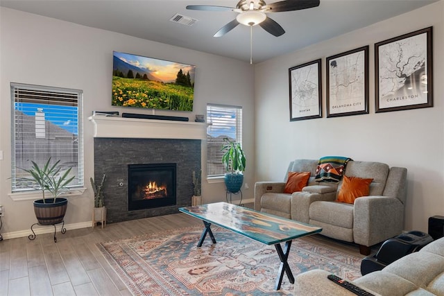 living area featuring baseboards, ceiling fan, wood finished floors, and healthy amount of natural light
