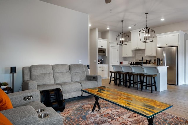 living area featuring light wood finished floors, recessed lighting, ceiling fan, and a chandelier