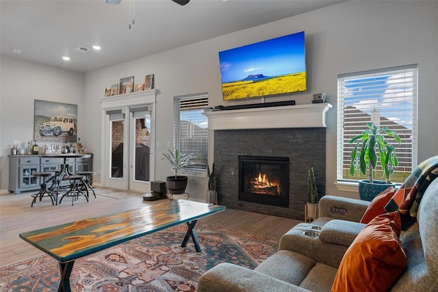 living area featuring wood finished floors, plenty of natural light, ceiling fan, a glass covered fireplace, and recessed lighting