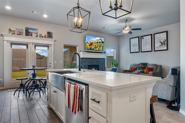 kitchen with open floor plan, wood finished floors, white cabinetry, a fireplace, and a sink