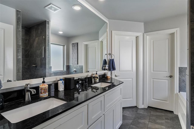 bathroom featuring double vanity, a tile shower, and recessed lighting