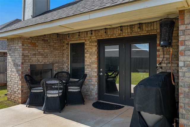 view of patio featuring french doors, an outdoor brick fireplace, area for grilling, and outdoor dining area