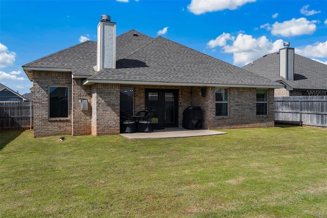 rear view of property with a shingled roof, a chimney, a patio, and brick siding