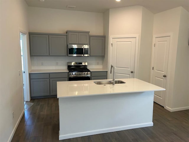 2933 NW 196th Pl, Edmond, OK 73012 - kitchen with stainless steel appliances, gray cabinetry, a sink, baseboards, and dark wood-style flooring