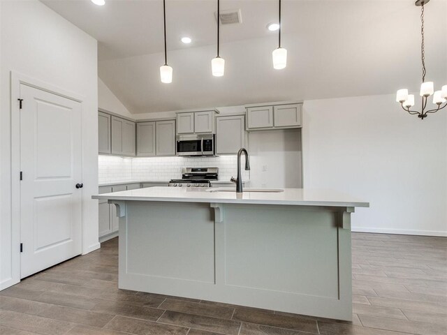 959 SE 16th Ter, Newcastle, OK 73065 - kitchen with appliances with stainless steel finishes, a sink, gray cabinetry, vaulted ceiling, and wood finished floors