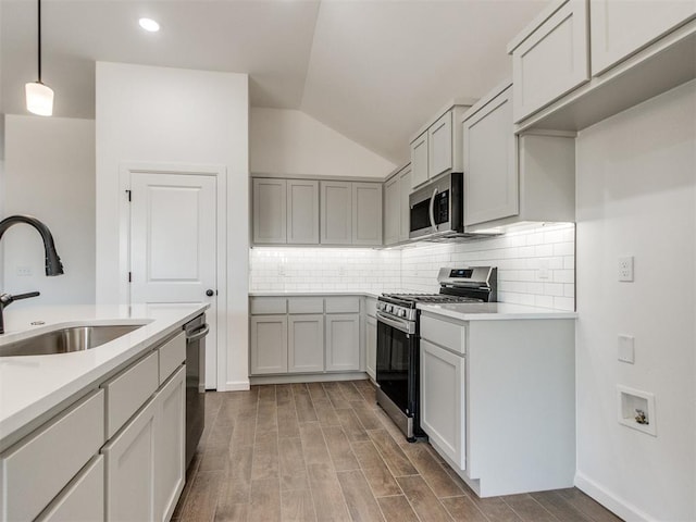 959 SE 16th Ter, Newcastle, OK 73065 - kitchen featuring stainless steel appliances, a sink, vaulted ceiling, light countertops, and decorative backsplash