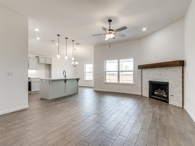 959 SE 16th Ter, Newcastle, OK 73065 - unfurnished living room with a sink, light wood finished floors, ceiling fan, a stone fireplace, and recessed lighting