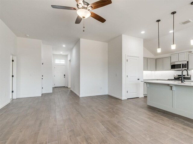 959 SE 16th Ter, Newcastle, OK 73065 - kitchen featuring stainless steel microwave, light countertops, a ceiling fan, tasteful backsplash, and light wood-style flooring