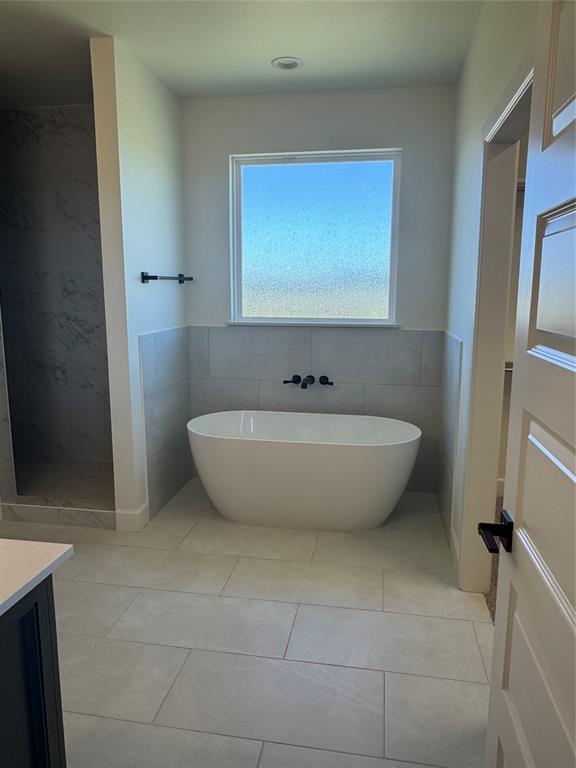 9596 Regado Ct, Guthrie, OK 73044 - bathroom with vanity, tile walls, a soaking tub, tiled shower, and tile patterned floors