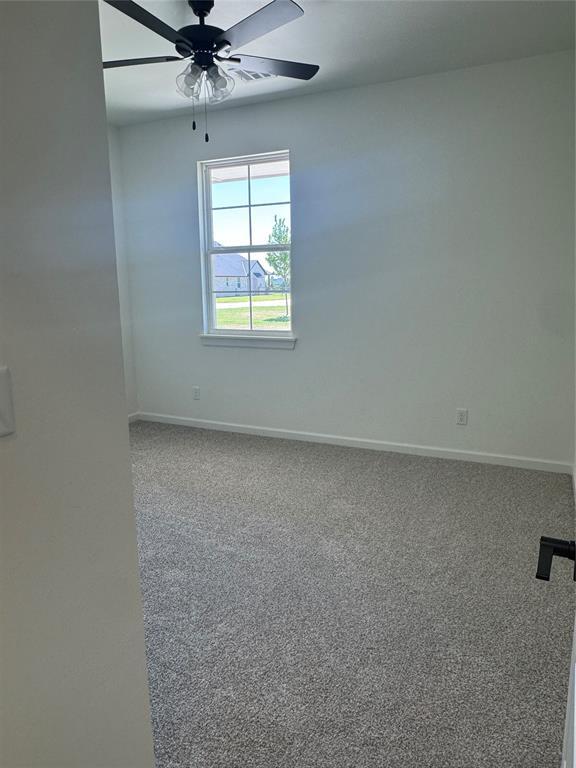 9596 Regado Ct, Guthrie, OK 73044 - carpeted spare room featuring ceiling fan and baseboards