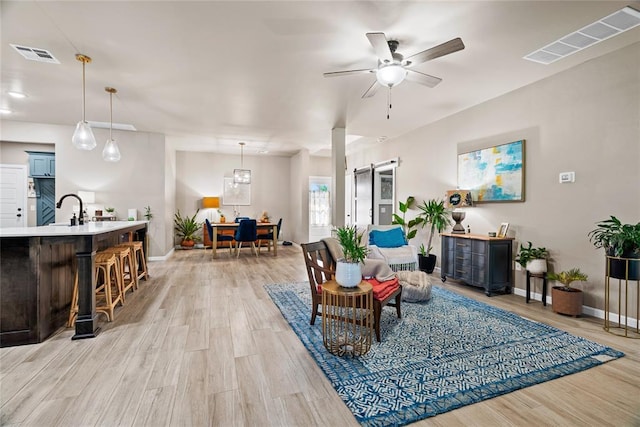 2803 Redwood Ct, Newcastle, OK 73065 - living room featuring a barn door, baseboards, light wood-style flooring, and ceiling fan