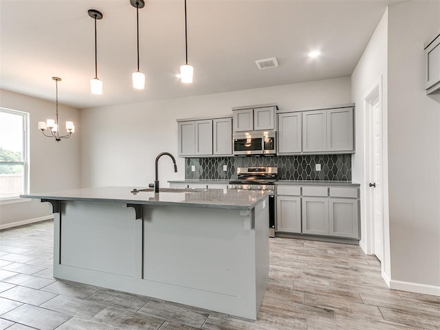929 SE 16th Ter, Newcastle, OK 73065 - kitchen featuring stainless steel appliances, gray cabinets, a sink, tasteful backsplash, and a chandelier