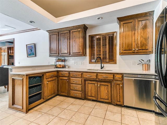 kitchen featuring dishwasher, a sink, light countertops, a peninsula, and tasteful backsplash