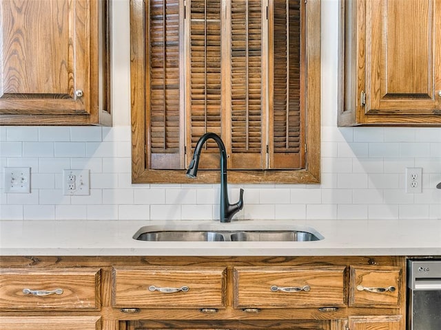 kitchen with a sink, decorative backsplash, brown cabinets, and light countertops