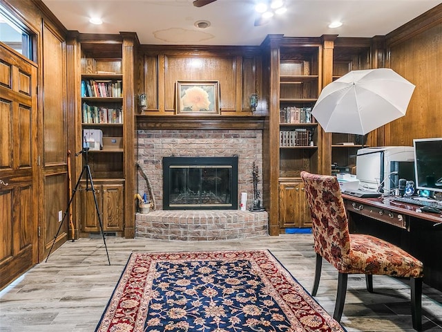 office featuring ceiling fan, wood walls, light wood-style floors, built in shelves, and ornamental molding