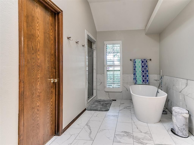 full bath with marble look tile flooring, tile walls, a stall shower, a soaking tub, and a wainscoted wall