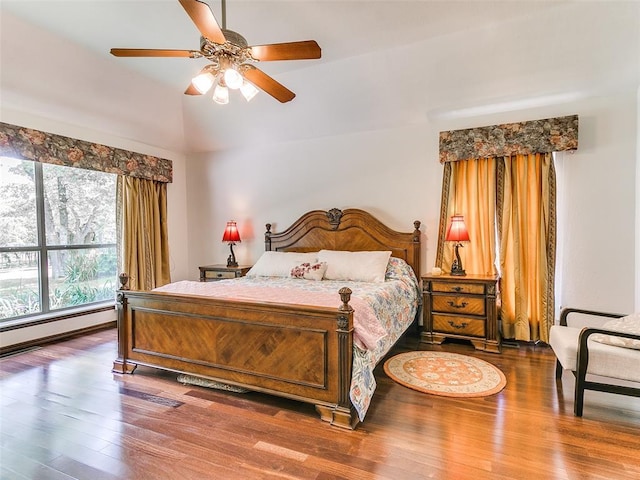 bedroom featuring wood finished floors, lofted ceiling, baseboard heating, and ceiling fan