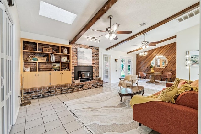125 Creek Hollow Dr, Choctaw, OK 73020 - living room featuring wood walls, light tile patterned floors, beam ceiling, a skylight, and a wood stove