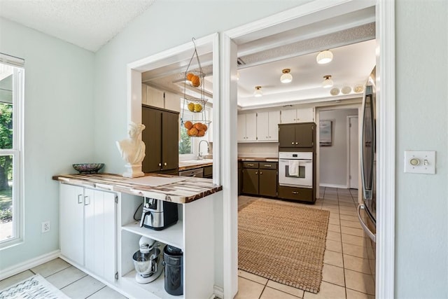 125 Creek Hollow Dr, Choctaw, OK 73020 - kitchen featuring white oven, light tile patterned floors, a textured ceiling, baseboards, and refrigerator