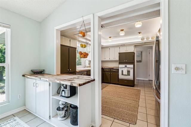 125 Creek Hollow Dr, Choctaw, OK 73020 - kitchen featuring white oven, light tile patterned floors, a textured ceiling, fridge, and baseboards