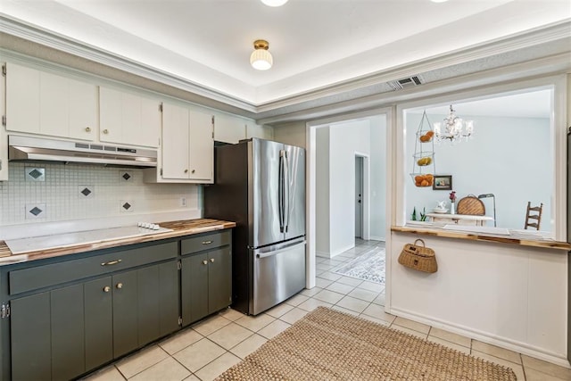 125 Creek Hollow Dr, Choctaw, OK 73020 - kitchen with under cabinet range hood, freestanding refrigerator, a chandelier, light tile patterned floors, and tasteful backsplash