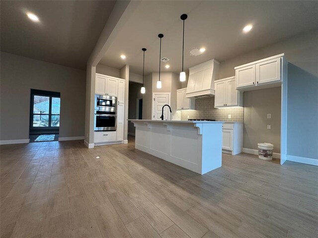1216 SW 139th St, Oklahoma City, OK 73170 - kitchen featuring appliances with stainless steel finishes, custom exhaust hood, tasteful backsplash, light wood finished floors, and white cabinets