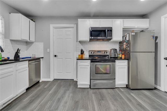 kitchen with appliances with stainless steel finishes, light wood-style flooring, dark countertops, decorative backsplash, and recessed lighting