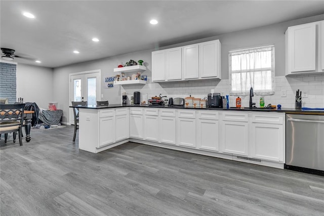 kitchen featuring dishwasher, a sink, dark countertops, backsplash, and recessed lighting