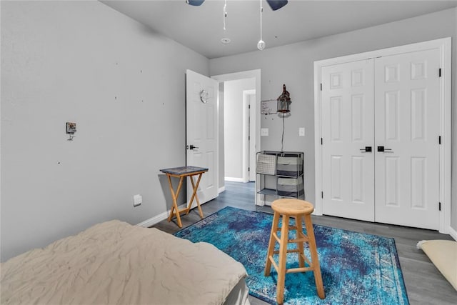 bedroom with dark wood-style flooring, baseboards, a closet, and a ceiling fan