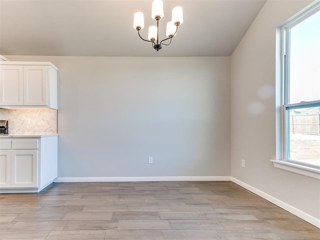 8617 NW 77th St, Oklahoma City, OK 73132 - unfurnished dining area with light wood-style flooring, a chandelier, and baseboards
