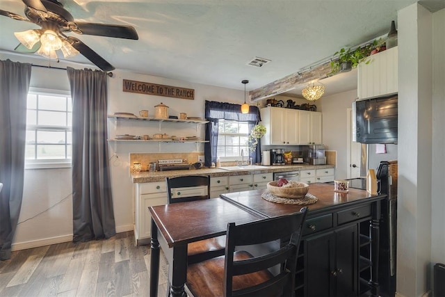 2316 E 68th St, Stillwater, OK 74074 - kitchen featuring a sink, ceiling fan, light wood-style floors, white cabinets, and dishwasher