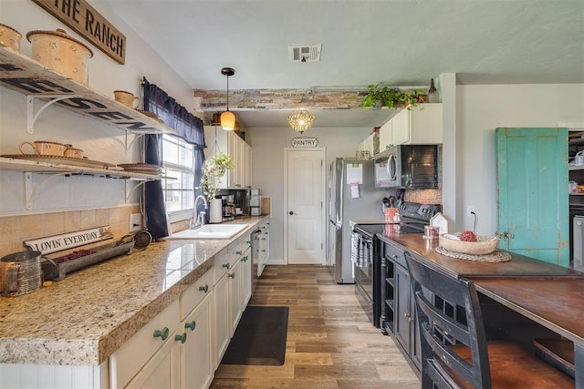 2316 E 68th St, Stillwater, OK 74074 - kitchen featuring stainless steel appliances, a sink, wood finished floors, white cabinets, and backsplash