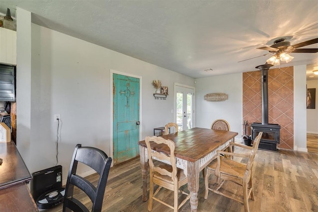 2316 E 68th St, Stillwater, OK 74074 - dining space with french doors, light wood finished floors, a wood stove, a ceiling fan, and baseboards