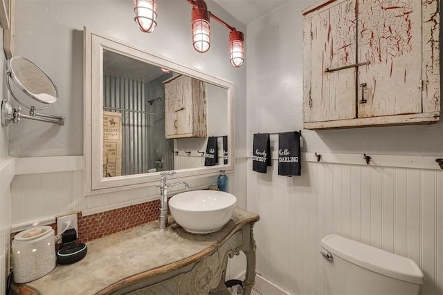 2316 E 68th St, Stillwater, OK 74074 - bathroom with a wainscoted wall, decorative backsplash, toilet, and vanity