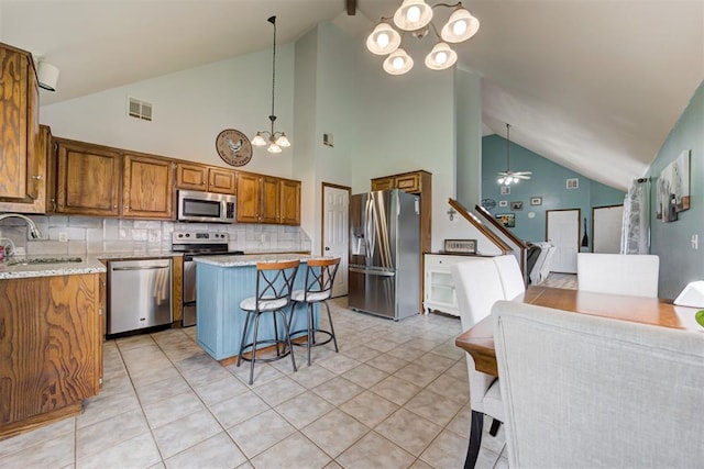 1312 SW 25th St, Moore, OK 73170 - kitchen featuring stainless steel appliances, a chandelier, a sink, brown cabinets, and tasteful backsplash