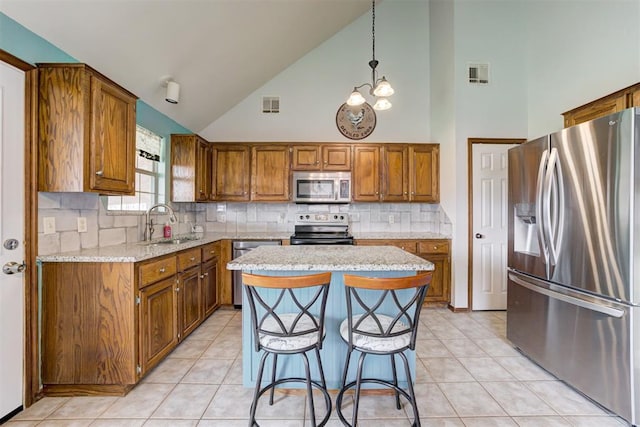 1312 SW 25th St, Moore, OK 73170 - kitchen featuring appliances with stainless steel finishes, brown cabinets, high vaulted ceiling, light tile patterned flooring, and a kitchen island