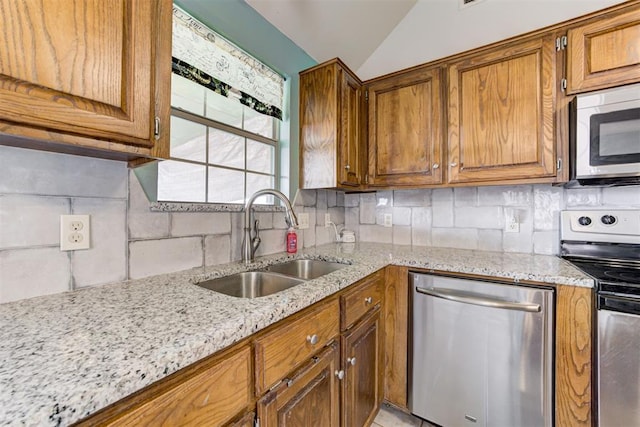 1312 SW 25th St, Moore, OK 73170 - kitchen with appliances with stainless steel finishes, a sink, brown cabinetry, light stone counters, and vaulted ceiling