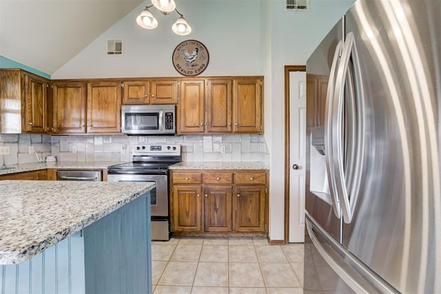 1312 SW 25th St, Moore, OK 73170 - kitchen featuring stainless steel appliances, light tile patterned floors, brown cabinetry, backsplash, and vaulted ceiling