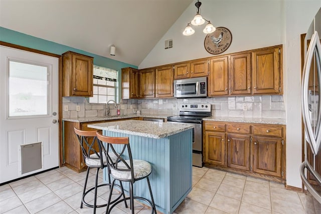 1312 SW 25th St, Moore, OK 73170 - kitchen featuring stainless steel appliances, a sink, brown cabinetry, decorative backsplash, and high vaulted ceiling