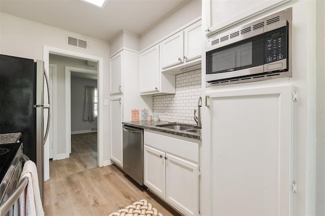 2424 Ashley Dr, The Village, OK 73120 - kitchen featuring stainless steel appliances, a sink, white cabinetry, tasteful backsplash, and light wood-style floors