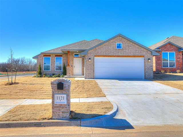 1121 Acacia Creek Dr, Yukon, OK 73099 - view of front of house with an attached garage, driveway, brick siding, a shingled roof, and a front yard