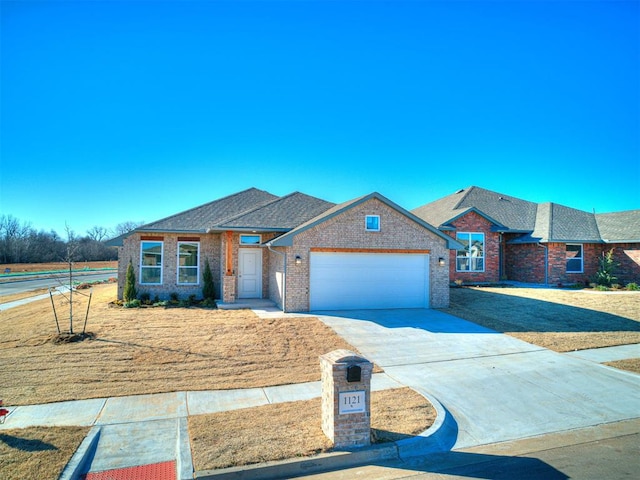1121 Acacia Creek Dr, Yukon, OK 73099 - view of front of house featuring a garage, driveway, brick siding, a shingled roof, and a front yard