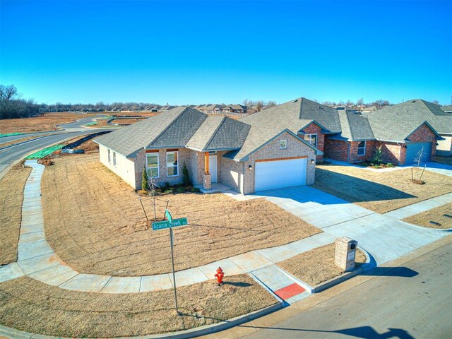 1121 Acacia Creek Dr, Yukon, OK 73099 - view of front of property with brick siding, driveway, a garage, and roof with shingles