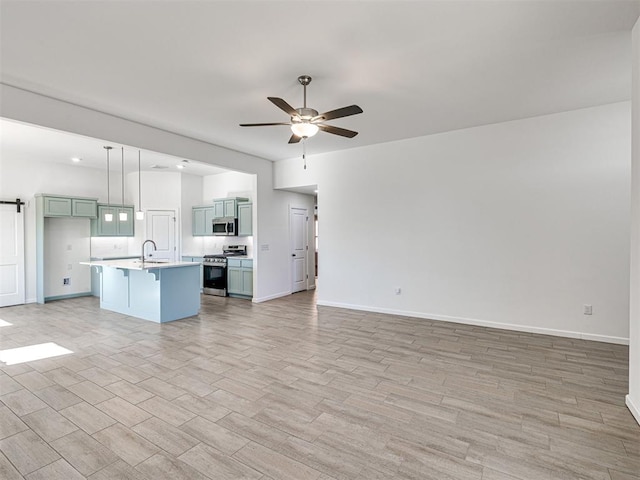 1121 Acacia Creek Dr, Yukon, OK 73099 - unfurnished living room with a ceiling fan, a barn door, baseboards, light wood-style flooring, and a sink