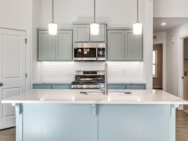 1121 Acacia Creek Dr, Yukon, OK 73099 - kitchen featuring appliances with stainless steel finishes, a sink, a kitchen bar, tasteful backsplash, and wood finished floors