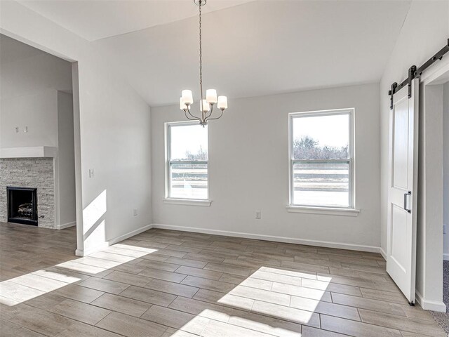 1121 Acacia Creek Dr, Yukon, OK 73099 - unfurnished dining area featuring a barn door, wood finished floors, lofted ceiling, a chandelier, and a fireplace
