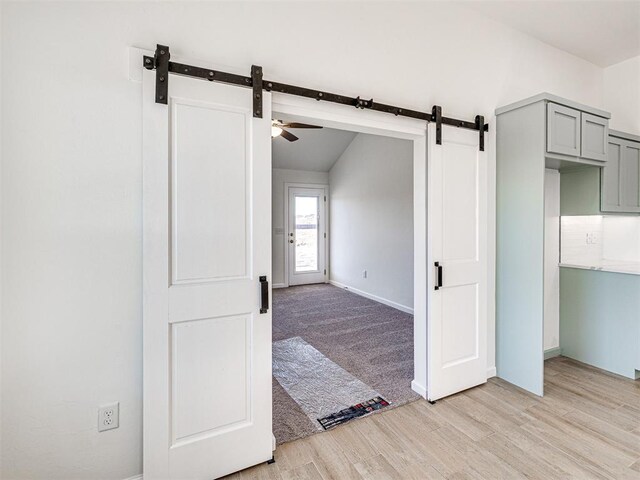 1121 Acacia Creek Dr, Yukon, OK 73099 - unfurnished room featuring a barn door, lofted ceiling, light wood-style floors, baseboards, and a ceiling fan