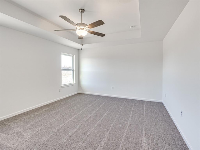 1121 Acacia Creek Dr, Yukon, OK 73099 - spare room featuring carpet flooring, a tray ceiling, ceiling fan, and baseboards